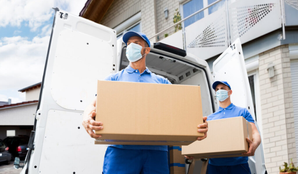 Movers In blue Uniform and face mask holding box